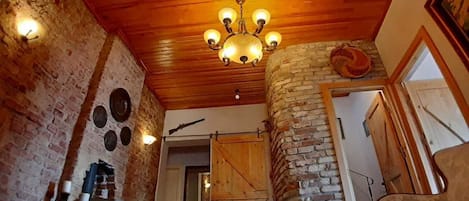 Un interior rústico con paredes de ladrillo visto, techo de madera y una araña.