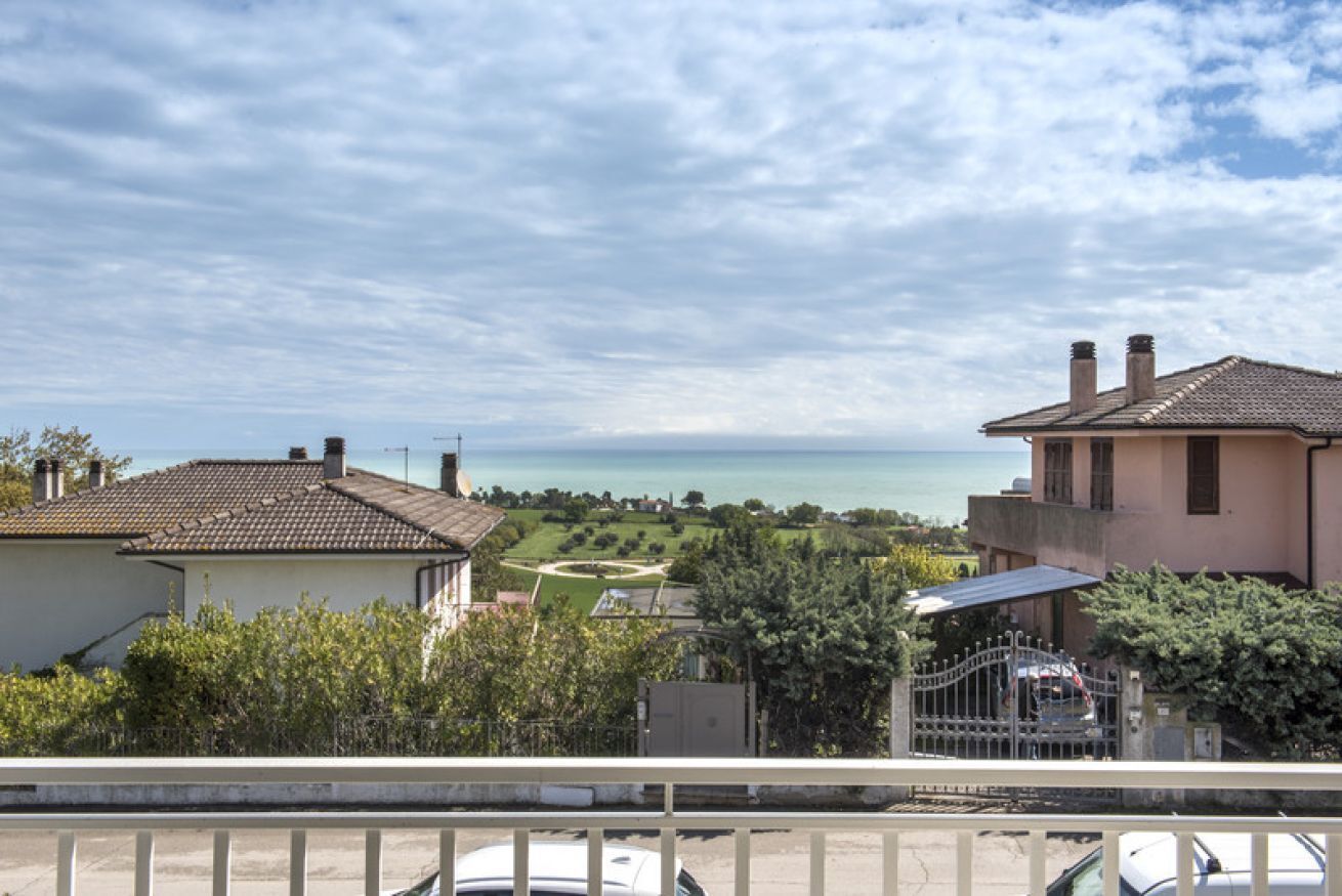 A residential area with houses, a view of the sea, and a clear sky.