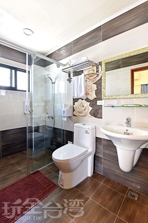 A modern bathroom with a glass-enclosed shower, a toilet, and a sink.