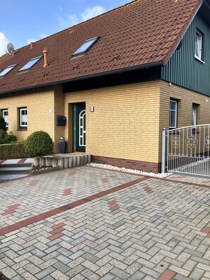 A two-story building with a brick facade, a green door, and a paved driveway.