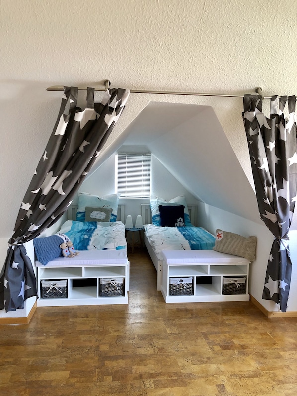 A bedroom with two bunk beds, star-patterned curtains, a small table, and a window with blinds.