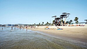 A beach with clear shallow waters, umbrellas, and beach chairs. - MALDIVAS Apartments (La Pineda)