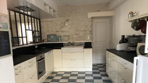 Una cocina compacta con armarios blancos, piso de baldosas blancas y negras en damero y electrodomésticos básicos.