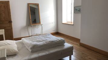 Een slaapkamer met een houten bed, een spiegel, een raam en een deur.