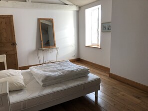 A bedroom with a wooden bed, a mirror, a window, and a door.