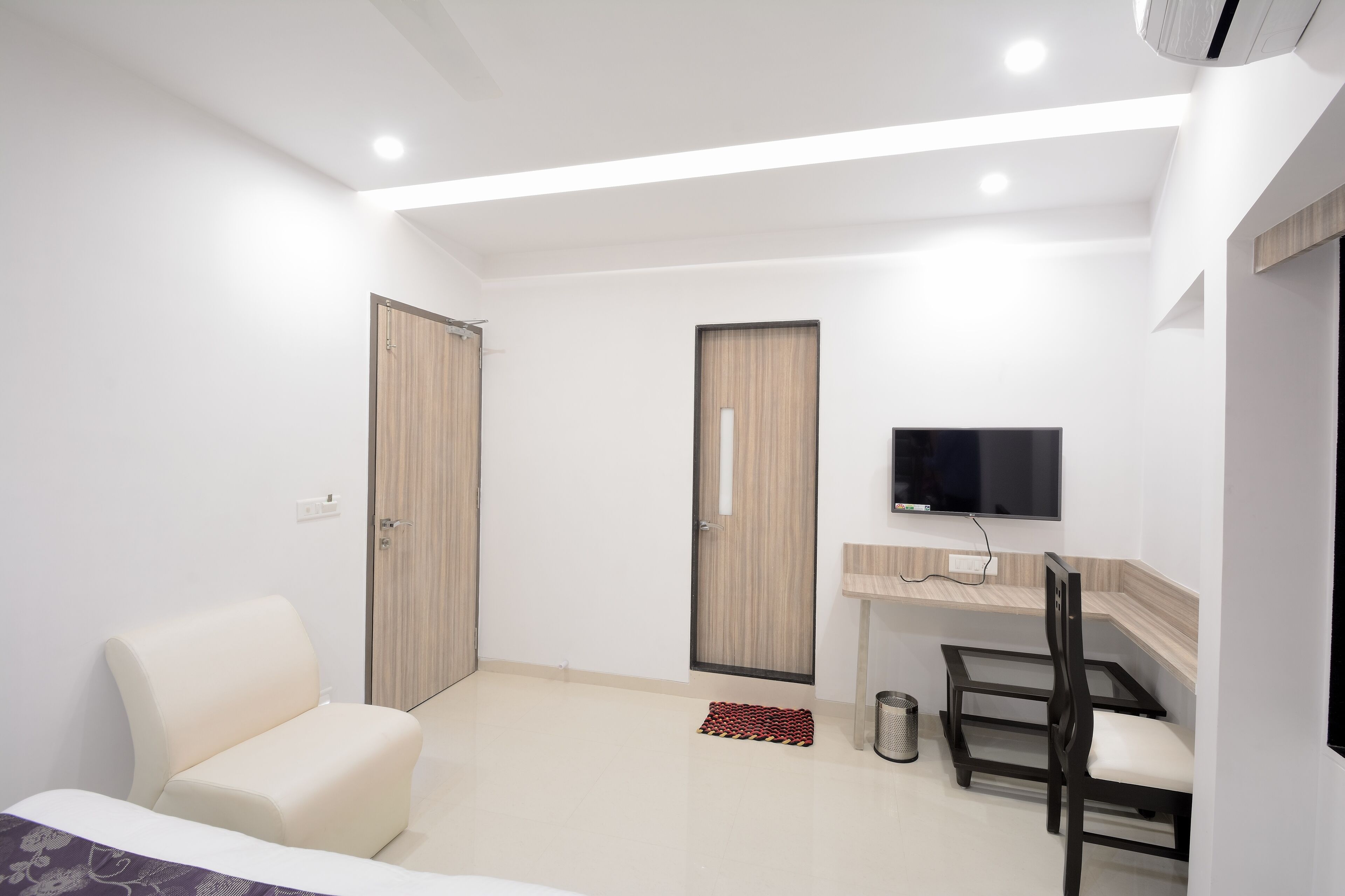 Une chambre d’hôtel moderne équipée d’un lit, d’un bureau, d’une chaise, d’une télévision et de deux portes.