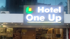 En hotelindgang med et skilt, der siger "Hotel One Up", og et "Velkommen"-skilt indenfor.