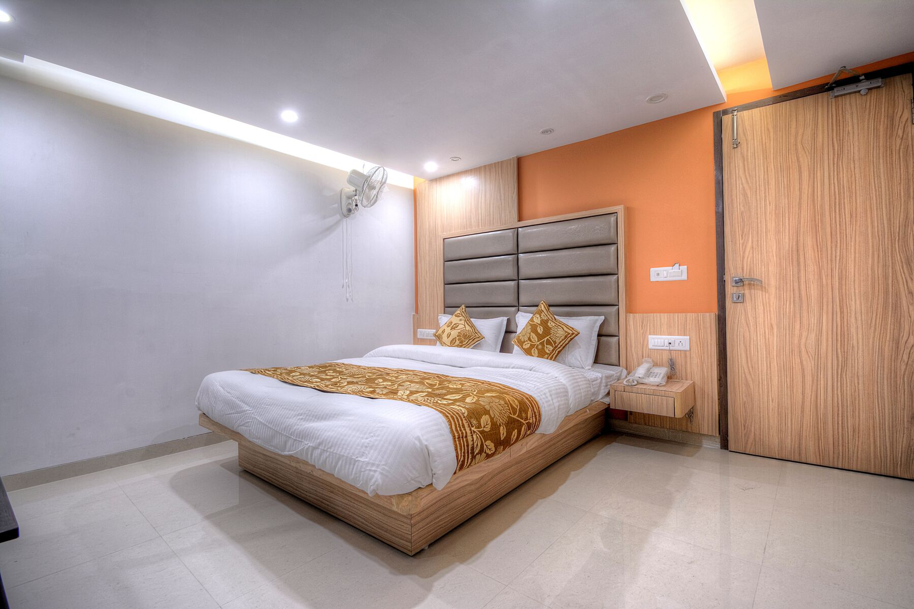 Une chambre à coucher moderne avec un grand lit, une armoire en bois et une table de chevet avec un téléphone.