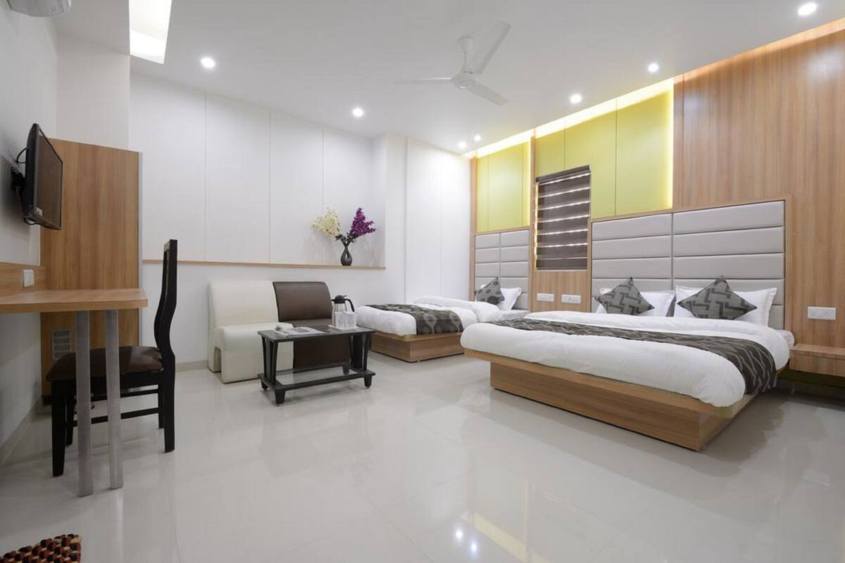 A modern hotel room with a large bed, a desk, a chair, and a TV.