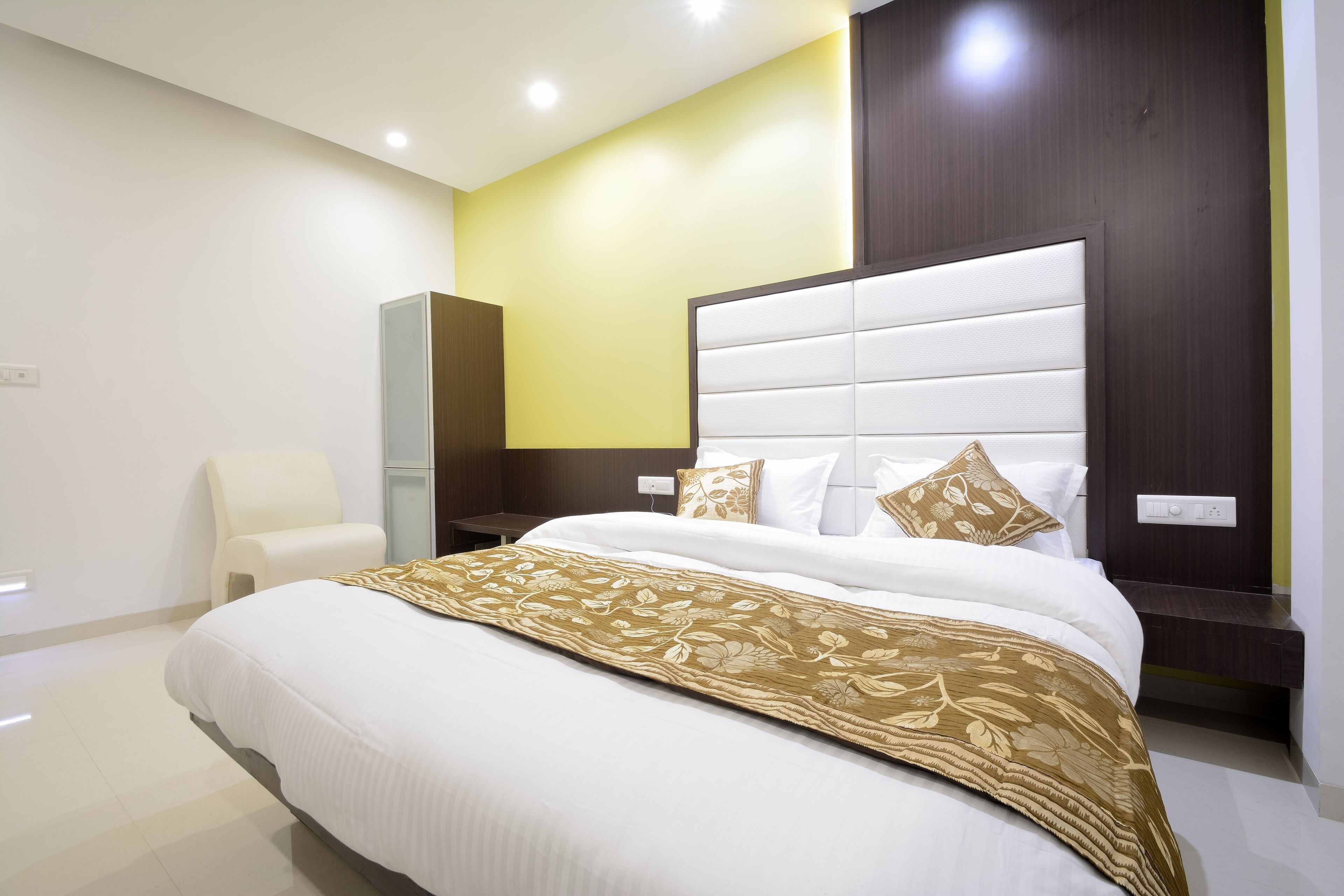 Une chambre d’hôtel moderne avec un grand lit, une table de chevet, une chaise et une armoire.