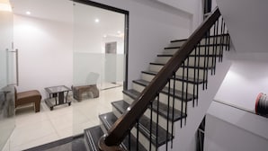 En moderne trappe med en glasdør ind til et opholdsområde med sofa, et lille bord og en stol.