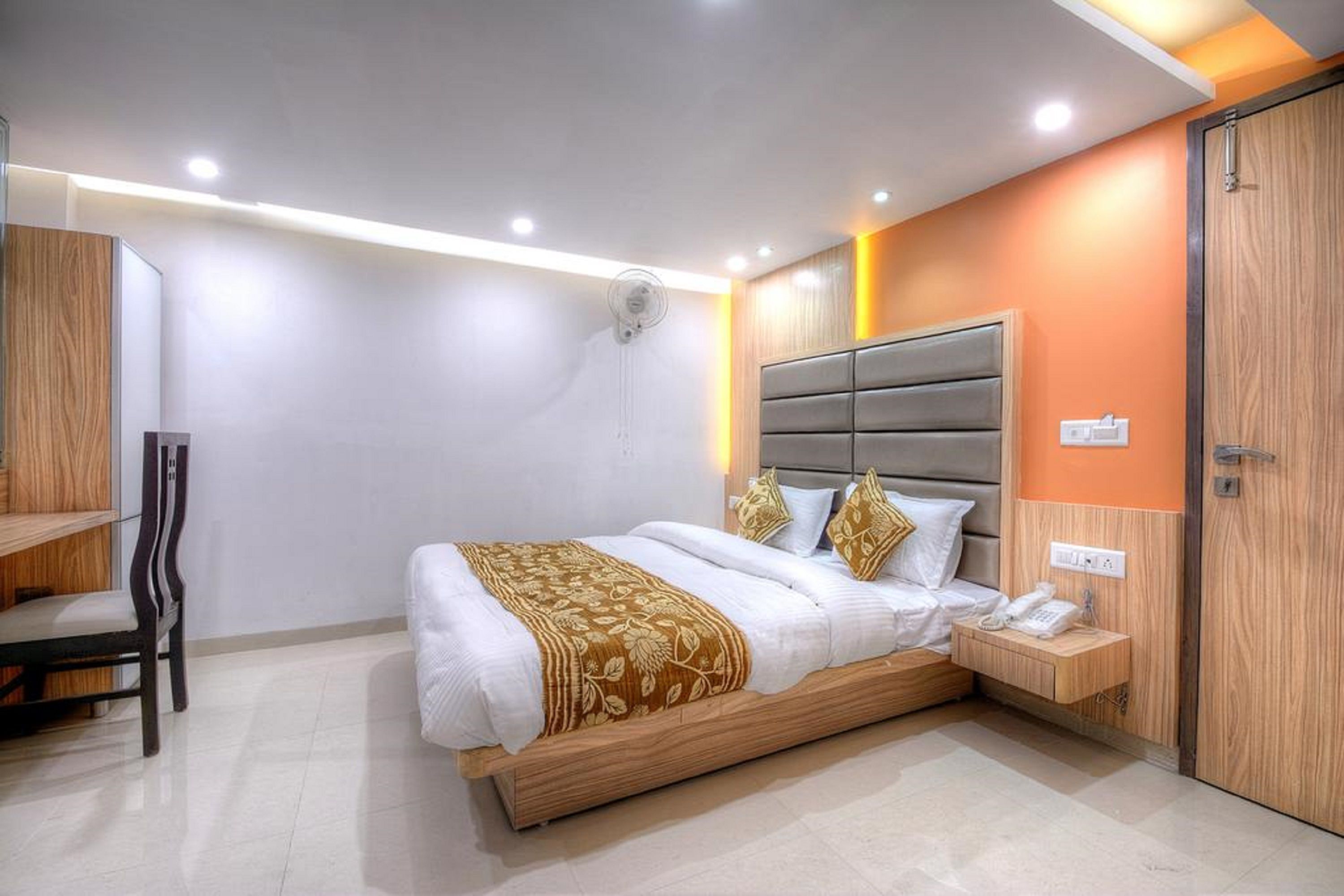 A modern hotel room with a large bed, bedside table, and a built-in wardrobe.