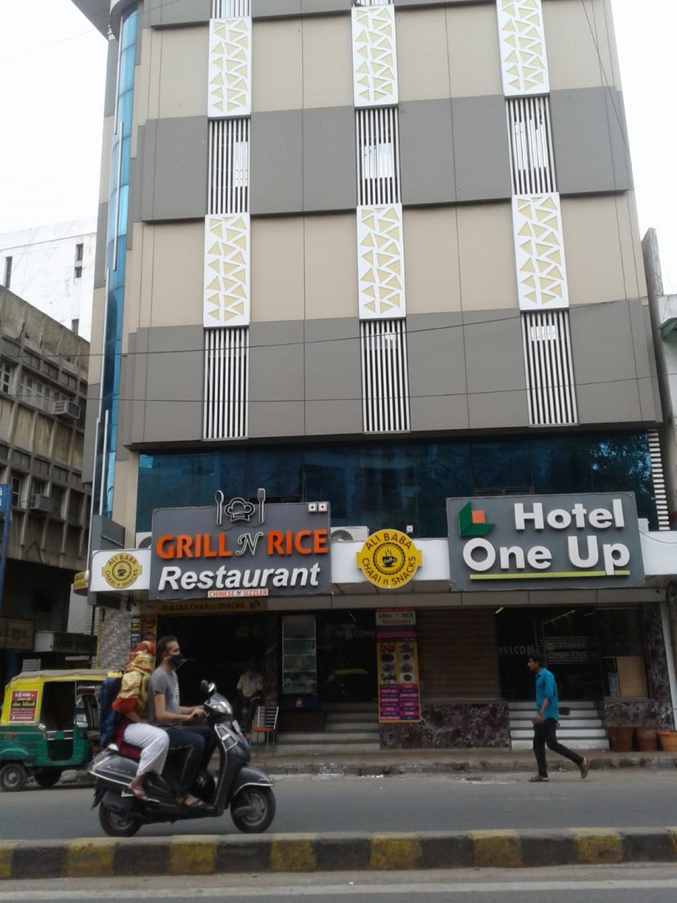 A building with a 'Grill n Rice Restaurant' and 'Hotel One Up' signs.
