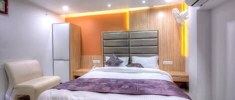 A modern bedroom with a large bed, a bedside table, a chair, and an air conditioning unit.