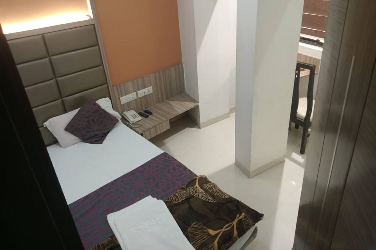 A hotel room with a bed, bedside table, and a small seating area.
