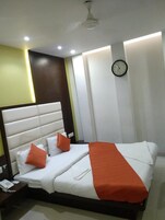 A hotel room with a bed, a bedside table with a phone, and a wall clock.