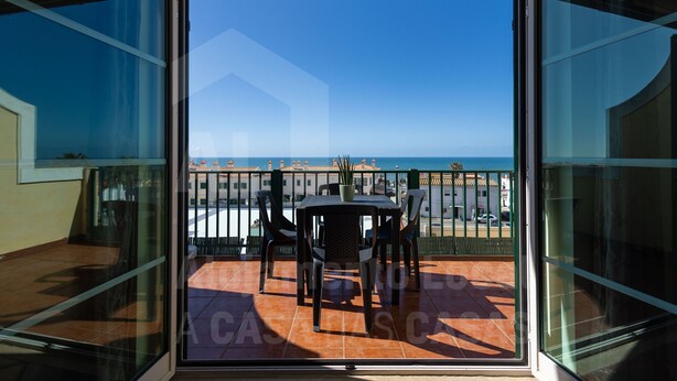 Ein Balkon mit Tisch und Stühlen mit Blick auf einen Strand und das Meer.