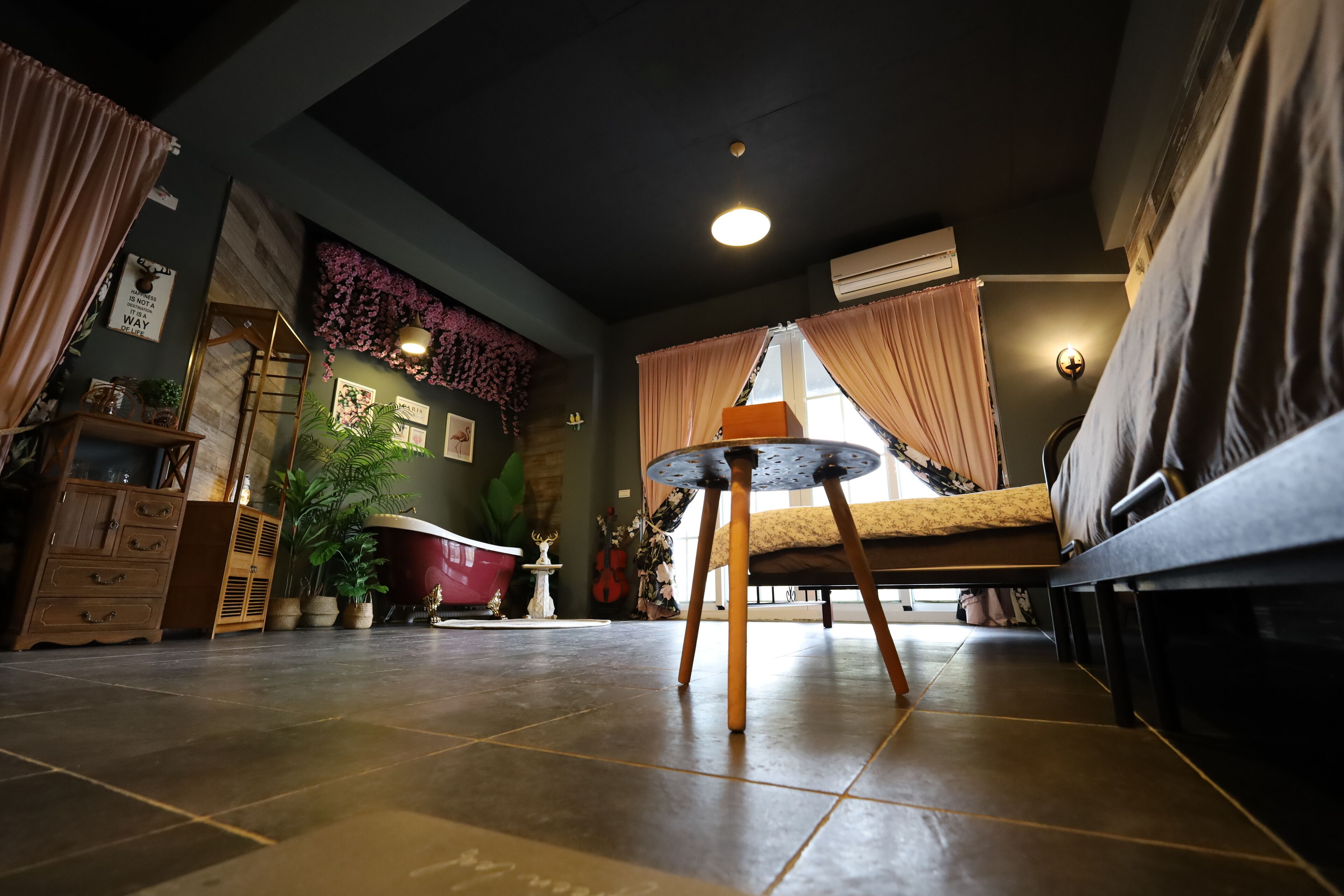 Una habitación acogedora con cama, una mesita, un aparador y una ventana con cortinas.