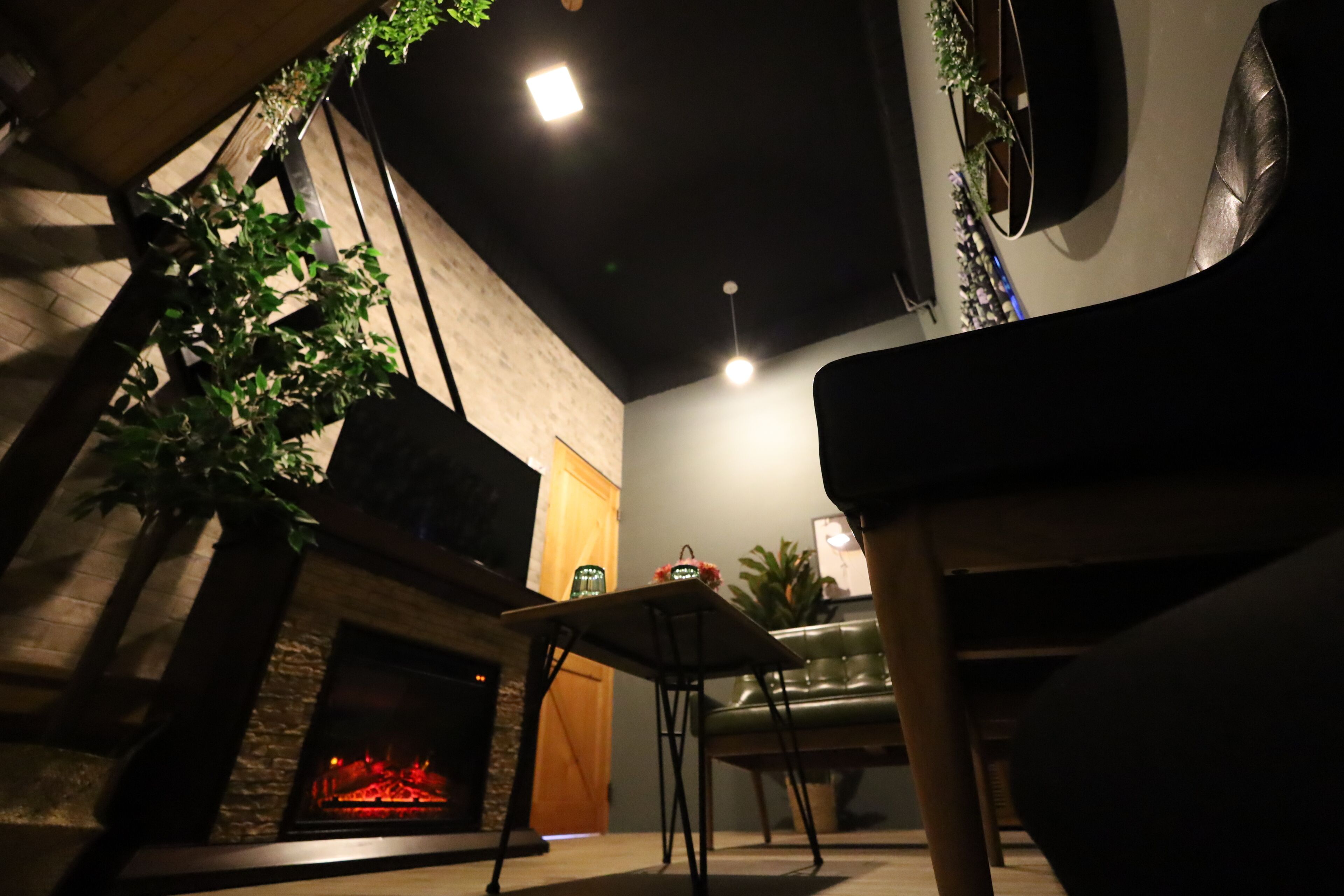 Ein gemütlicher Innenraum mit Kamin, einem grünen Sofa und einem kleinen Tisch.