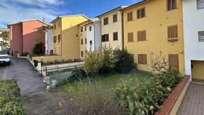 A row of residential buildings with a paved driveway and a small garden area. - N194 - Numana, large three-room apartment with garden (Numana)