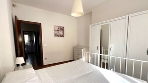 A bedroom with a bed, a nightstand, a dresser, a wardrobe, and a hanging light fixture. - N194 - Numana, large three-room apartment with garden (Numana)