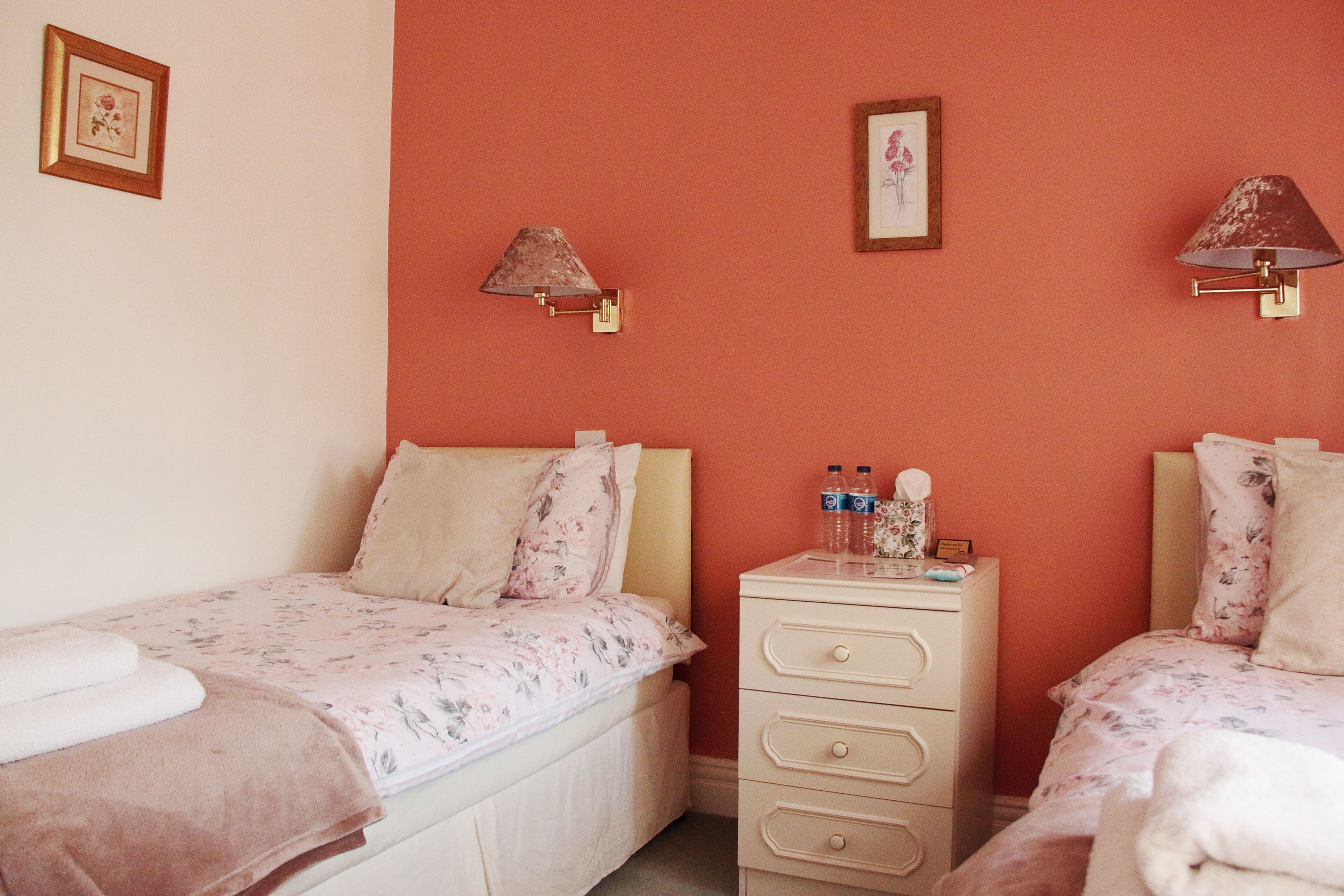 Un dormitorio con dos camas individuales, un aparador y dos lámparas de pared.