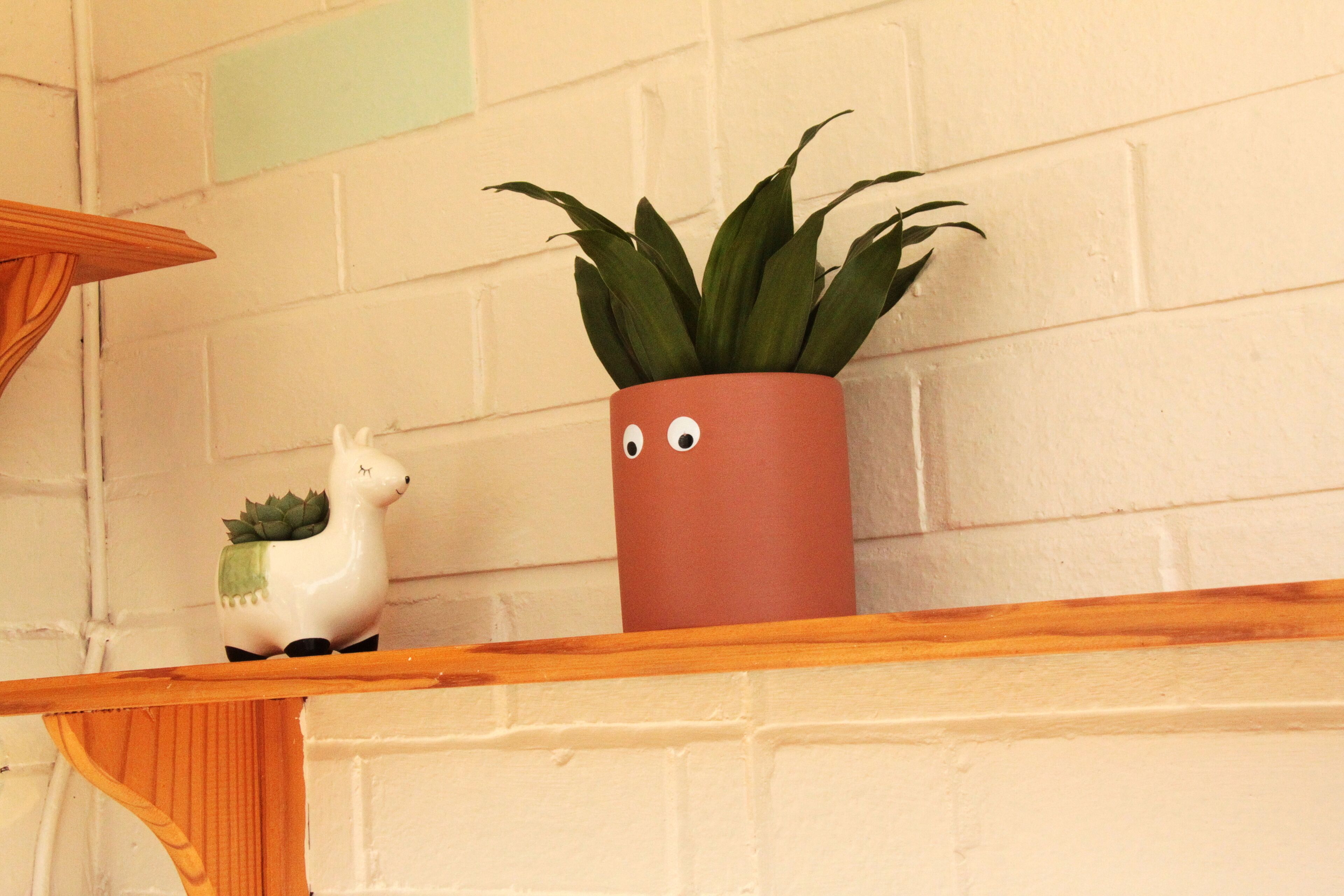 Una estantería con una planta en maceta y una figurita de cerámica.