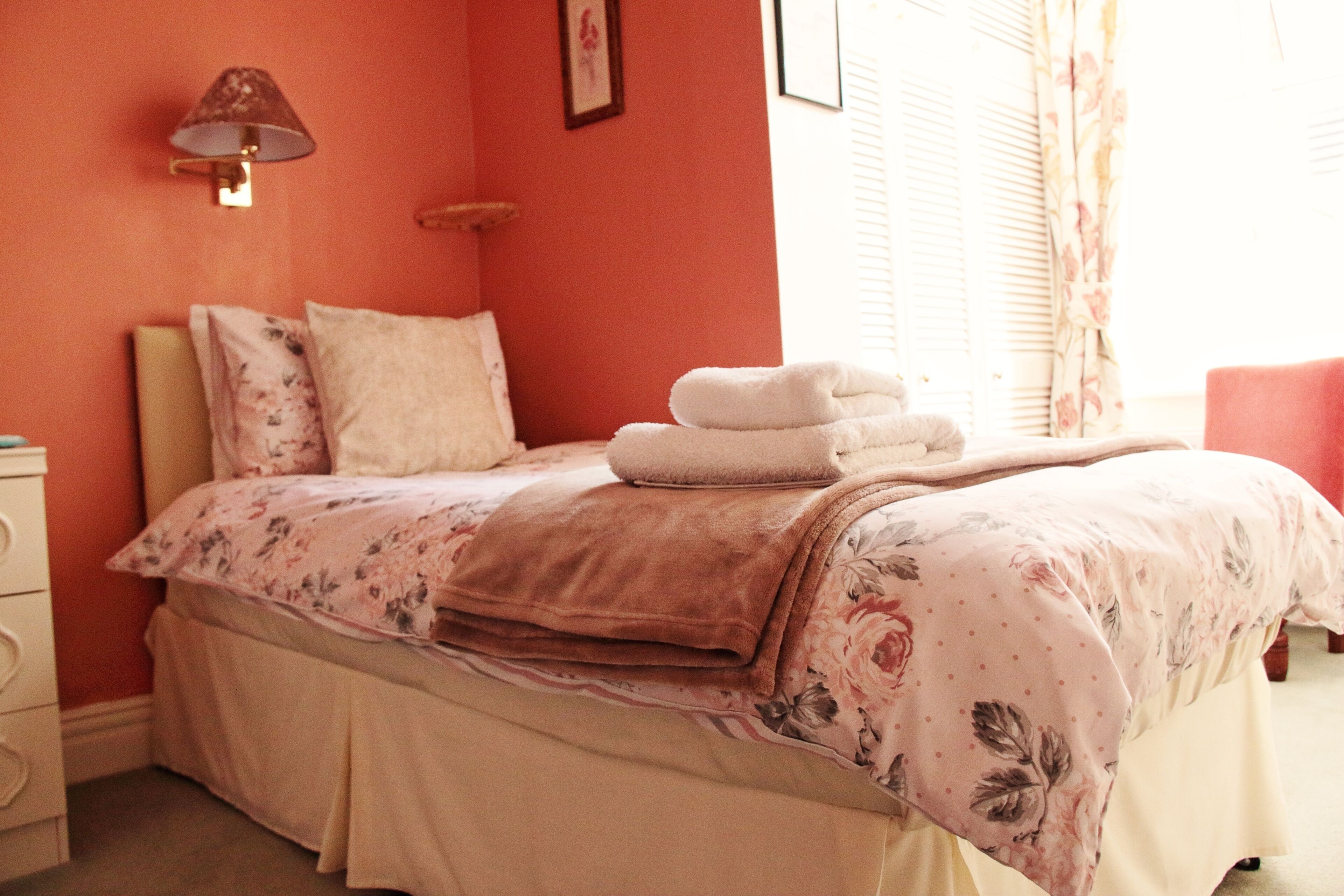 A bedroom with a bed, pillows, a bedside table, and a lamp.