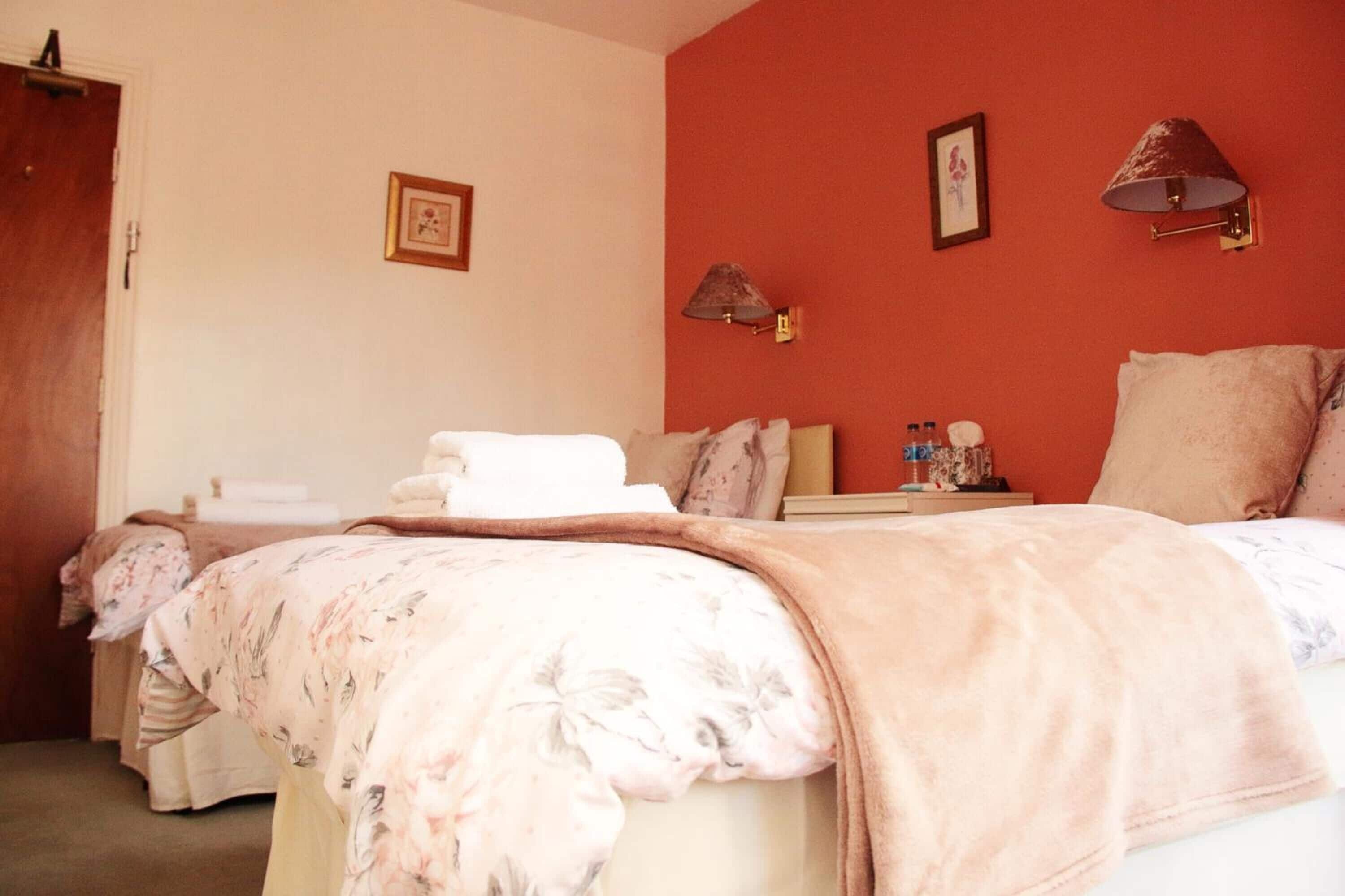 A hotel room with a bed, a bedside table with a lamp, and a wall-mounted picture.