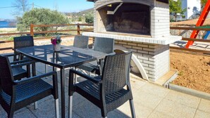 An outdoor patio with a brick barbecue grill, a table, and four chairs. - Lovely apartment in villa for 2 guests with A/C, WIFI, TV and terrace (Biograd Na Moru)