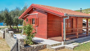 A red wooden cabin with a tiled roof, stone walls, and a small porch. - Lovely apartment in villa for 2 guests with A/C, WIFI, TV and terrace (Biograd Na Moru)