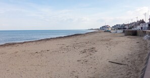 Une plage avec une barrière en béton, des bâtiments en arrière-plan et un ciel dégagé.