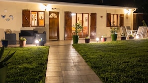 Una casa con vialetto lastricato che conduce a una porta, circondata da erba e piante in vaso.