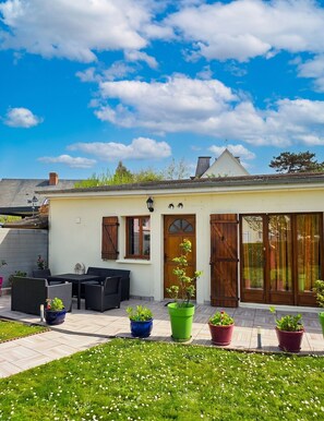 Une maison dotée d’un patio, de meubles d’extérieur et de plantes en pot.