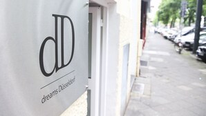Un letrero con las letras "CD" y las palabras "dreams Düsseldorf" en la fachada de un edificio.