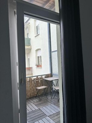 An open door to a balcony with a view of a building, a table, and two chairs. - dreams Düsseldorf (Düsseldorf)