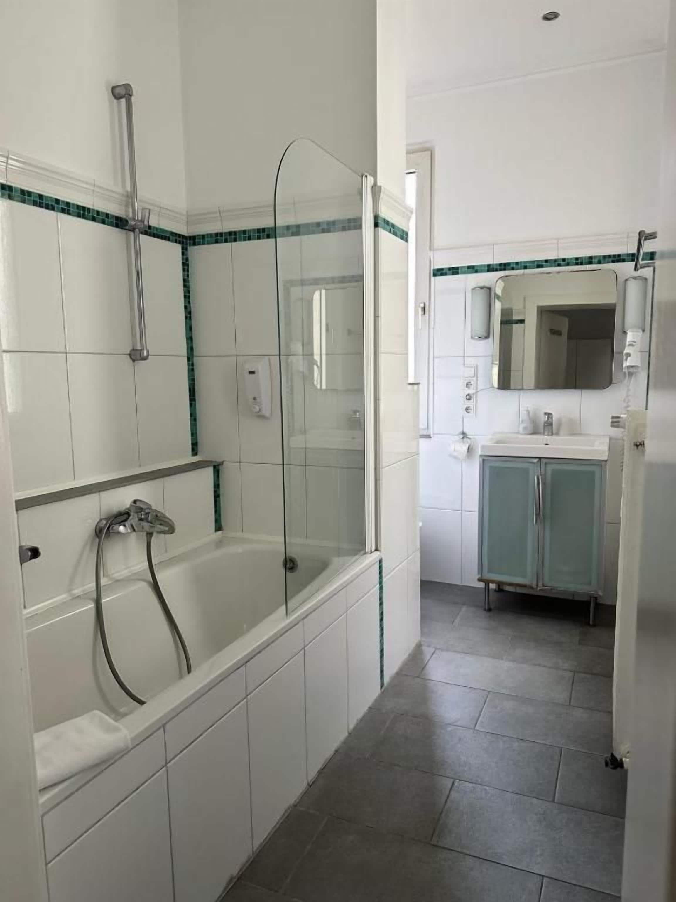 Une salle de bain avec une douche à parois de verre, une baignoire blanche et un meuble-lavabo avec un miroir.