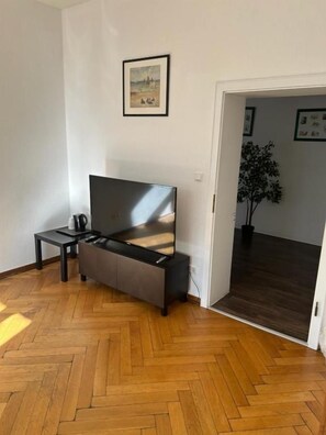 Una habitación con sofá, una mesa de centro, un televisor de pantalla plana y una planta en maceta.