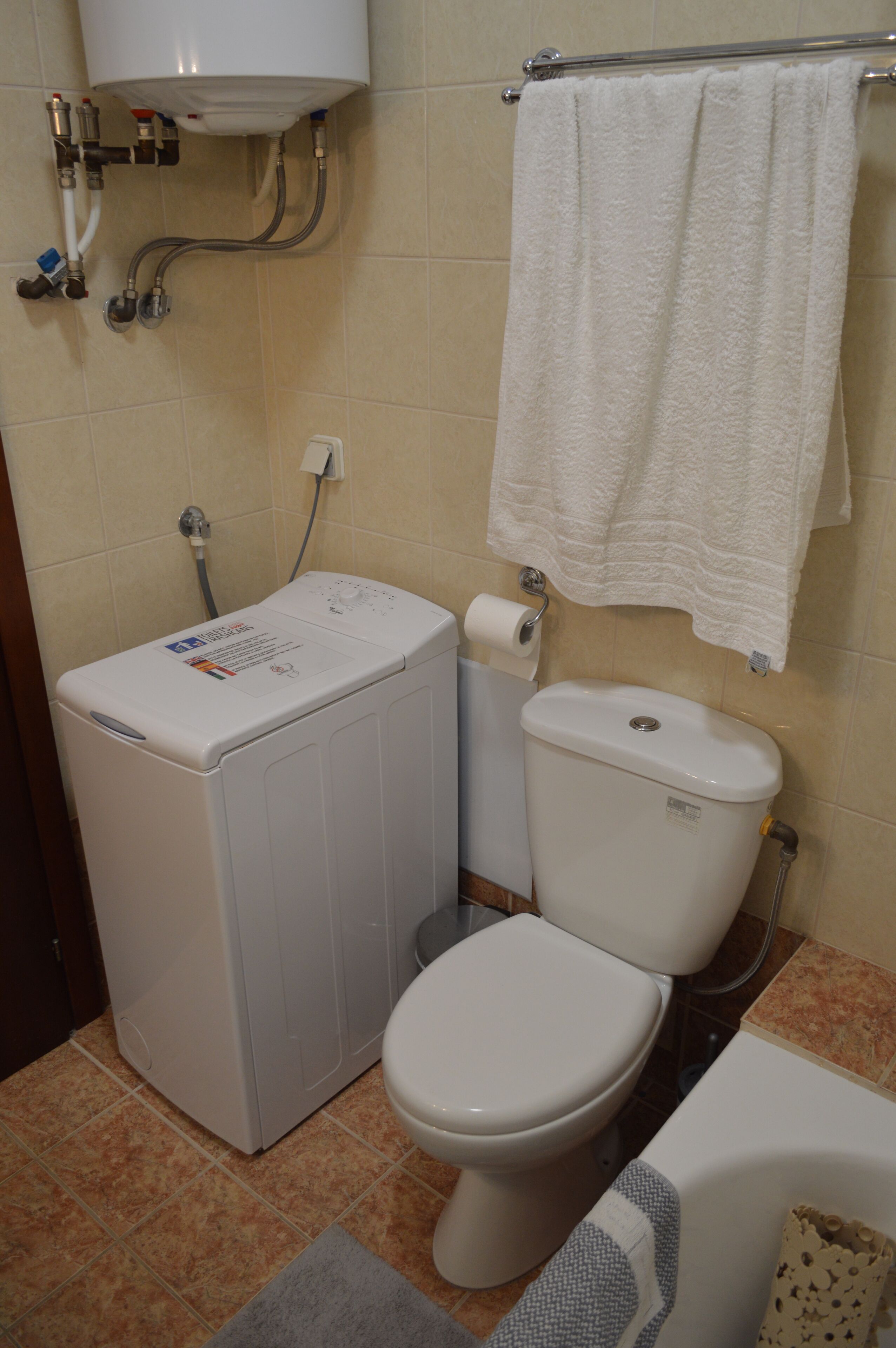Une salle de bain équipée d’un lave-linge, de toilettes et d’un porte-serviettes.