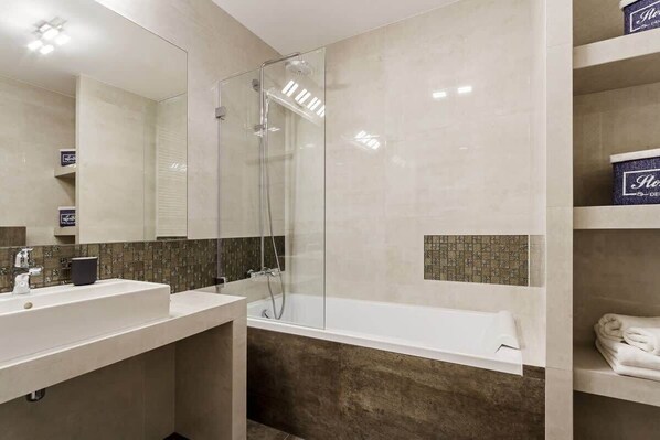 Un baño moderno con ducha envuelta en vidrio, un espejo grande y una bañera.