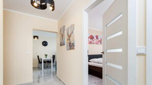 A hallway with a dining area, a bed, and artwork on the walls.