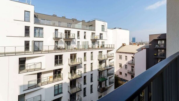 A multi-story residential building with balconies, large windows, and a clear sky.