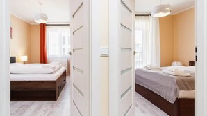 A hotel room with a bed, bedside table, lamp, and a view of the street.