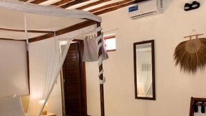 Una habitación con una cama, techo de madera, aire acondicionado de pared y un perchero mural.