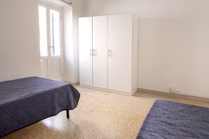 Ein Zimmer mit zwei Betten, einem Kleiderschrank und einer Tür.