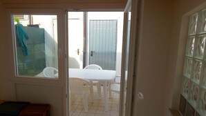 A room with a sliding glass door leading to an outdoor patio with a white table and chairs.