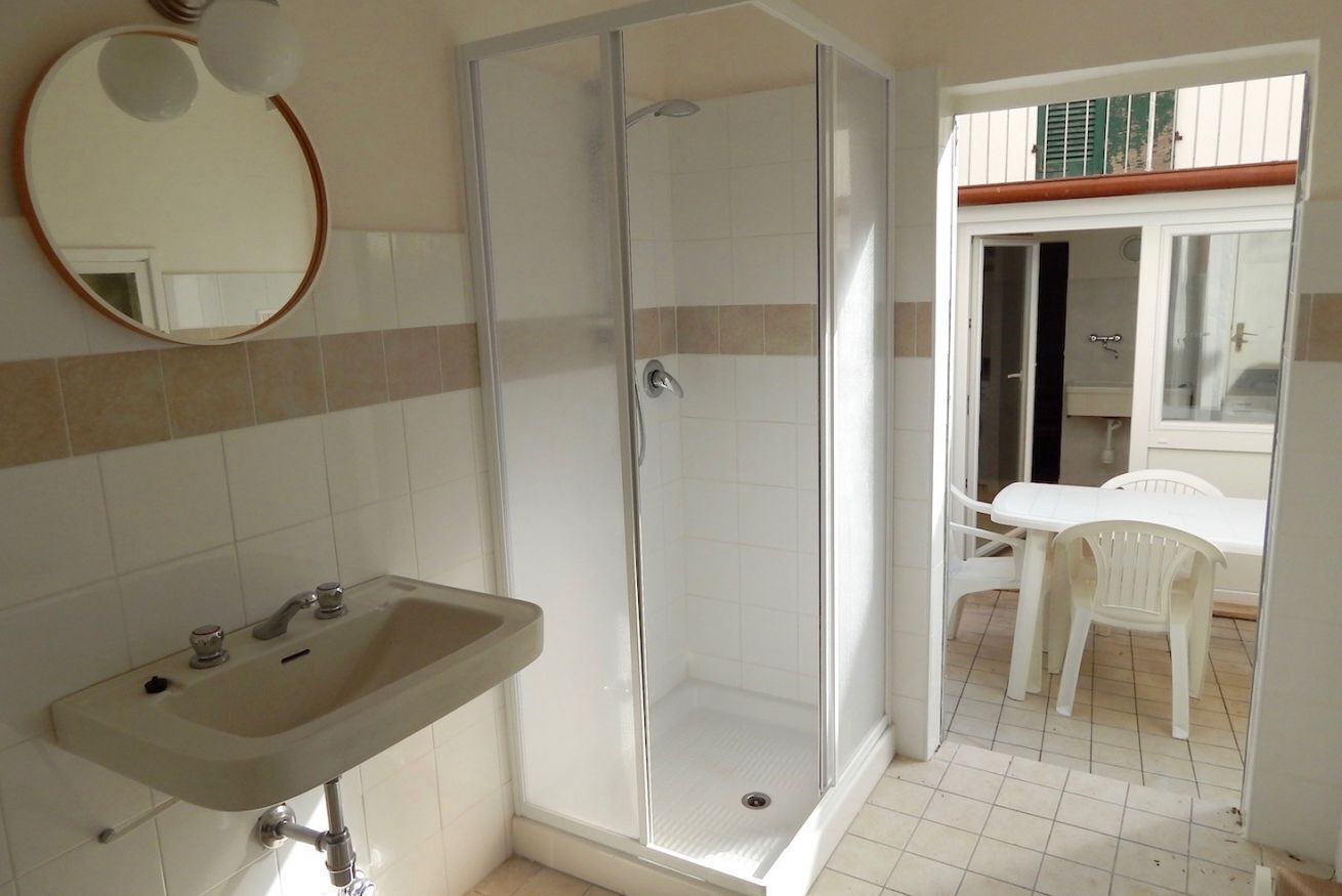 A bathroom with a sink, shower, and a table with chairs.