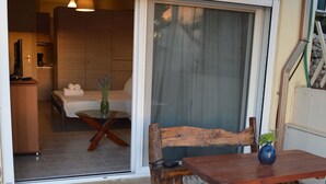 A wooden bench and table with a vase on a patio with a sliding glass door leading to a bedroom. - Best House Petit Pylos Messinias (Pylos-Nestoras)