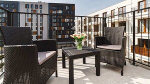 A balcony with wicker furniture and a vase of flowers. - Stylish Apartment near the Station | Parking | Balcony (Kraków)