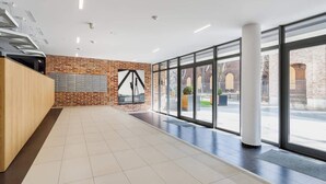 A spacious lobby with a brick wall, large windows, and a reception desk. - Stylish Apartment near the Station | Parking | Balcony (Kraków)